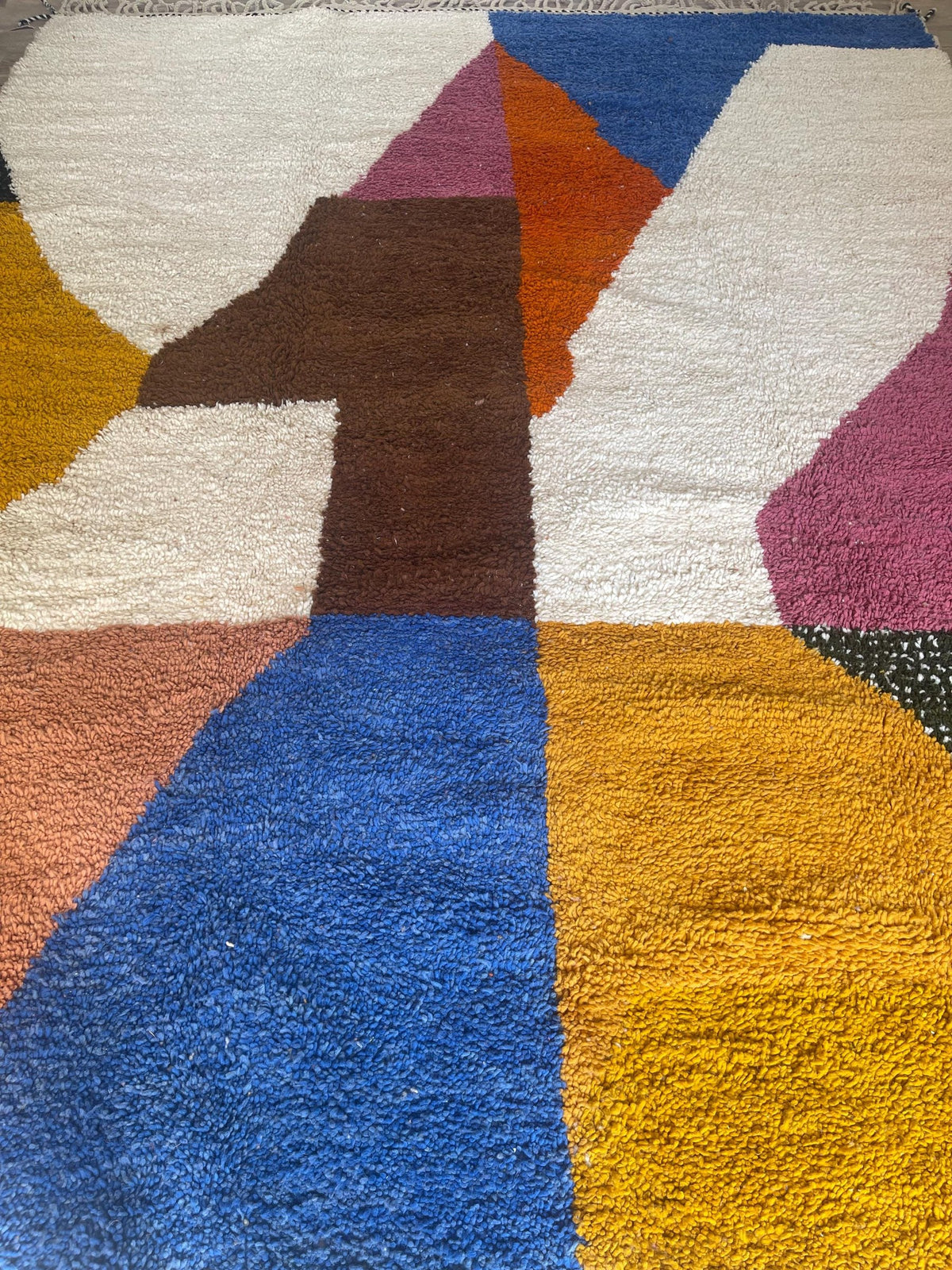 Gros plan sur un détail du tapis berbère Nassour, poil long et motif multicolore vus de près