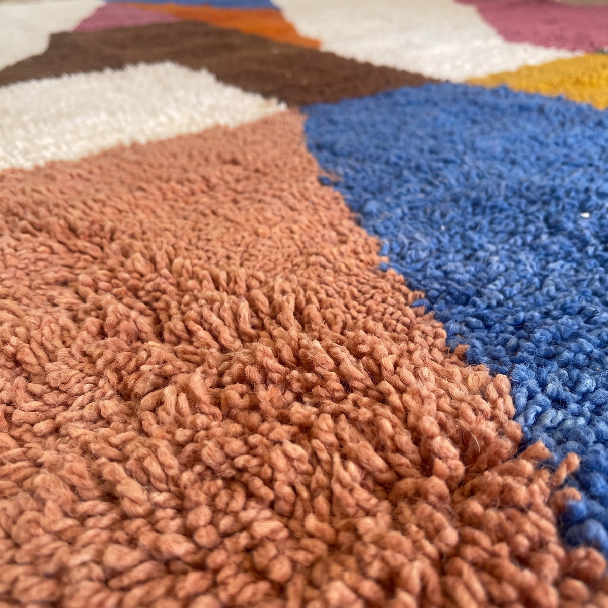 Gros plan sur un motif du tapis berbère Nassour, aplats géométriques, haut écru et bleu