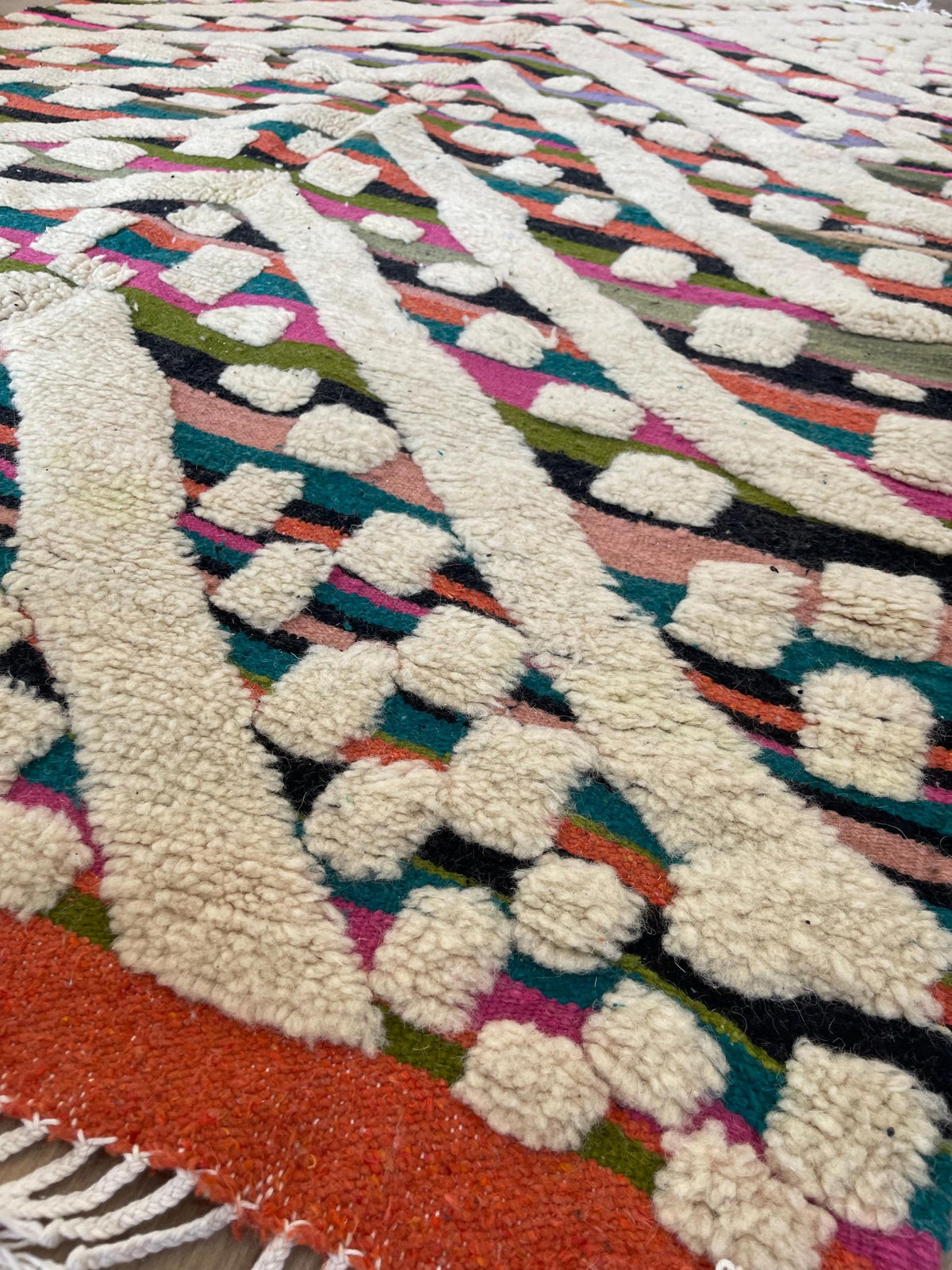 Gros plan sur le coin relevé du tapis berbère Yebrir, épaisseur du poil moyen et dos tissé à la main
