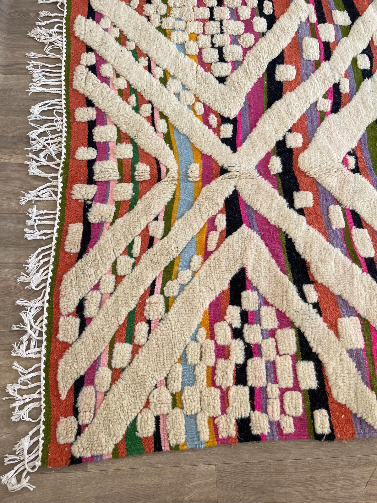 Gros plan sur les franges du tapis berbère Yebrir, blanches libres, nouées à la main