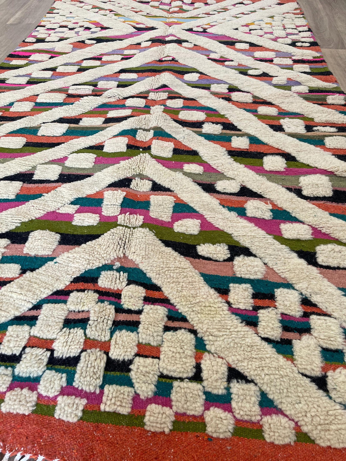 Gros plan sur un détail du tapis berbère Yebrir, poil moyen et motif multicolore vus de près