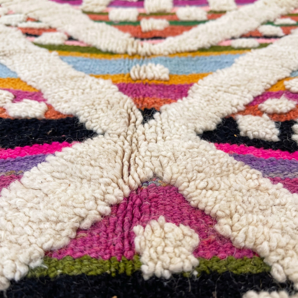 Gros plan sur un motif du tapis berbère Yebrir, kilim à rayures horizontales orange, fuchsia, noir, vert
