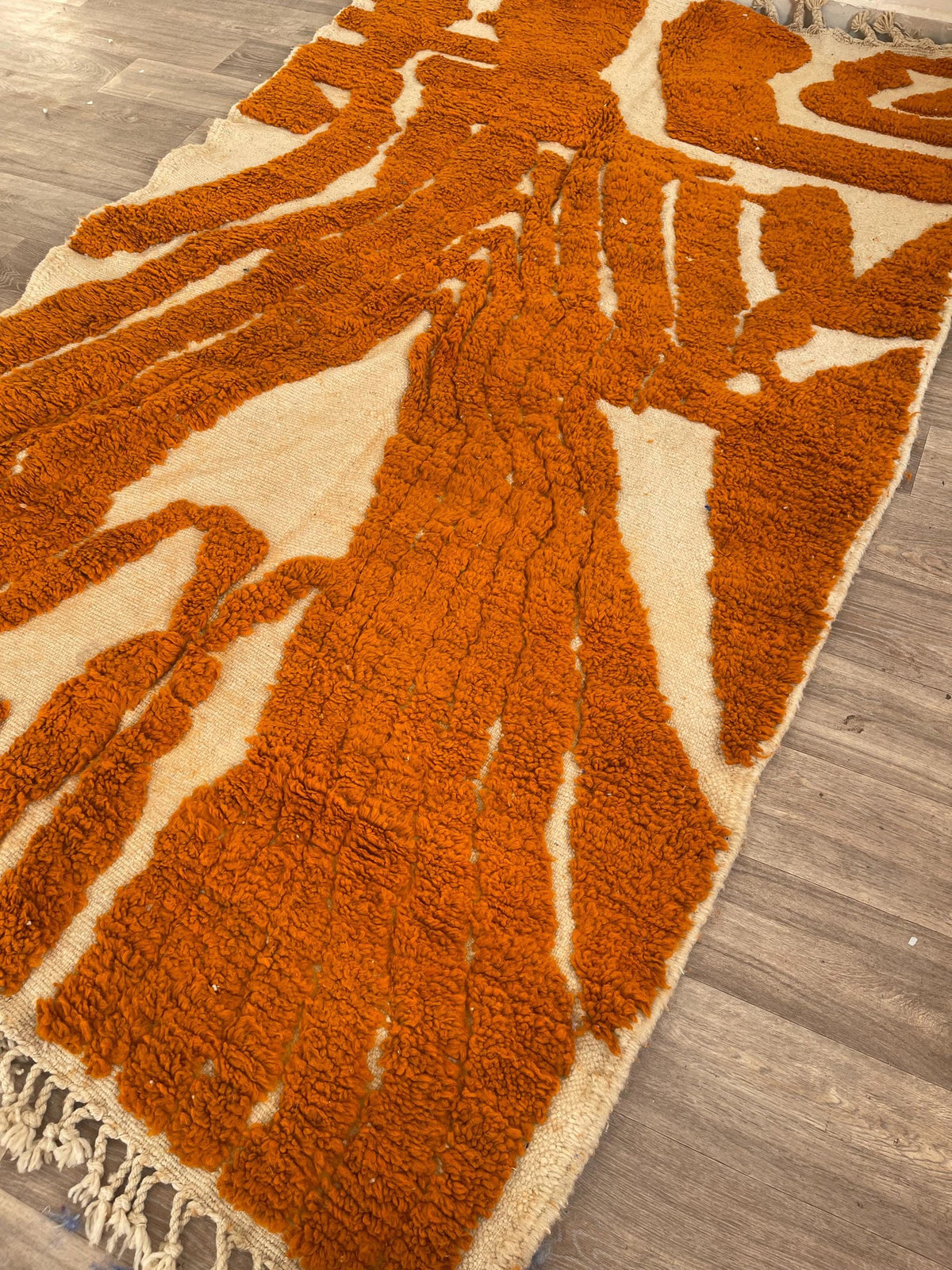 Chebbi graphic Berber rug in orange and white on the floor, seen from the side, hand-knotted in Morocco