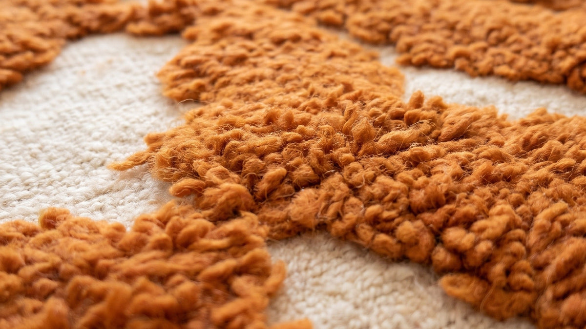 Gros plan sur la laine du tapis berbère Chebbi, poil orange et blanc noué à la main
