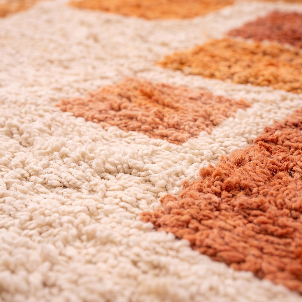 Gros plan sur un motif du tapis berbère Tabburt, fond écru à poil long, grande arche orange