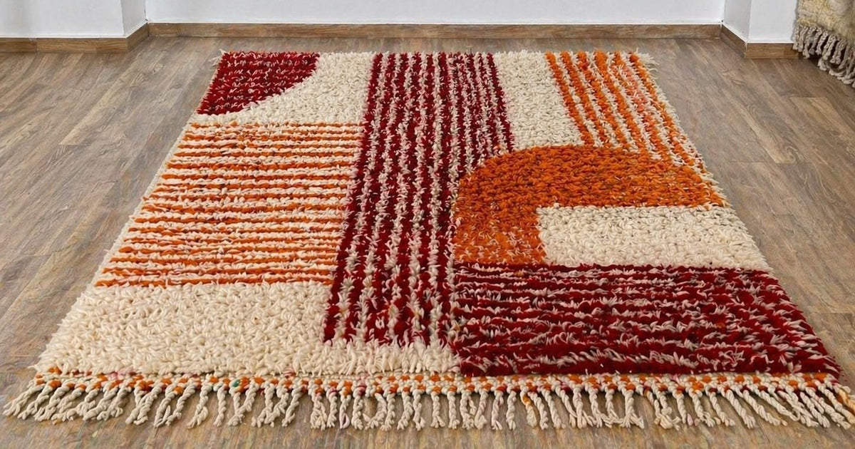 Tawwurt Berber rug, graphic, in orange and burgundy, on the floor, seen from the side, hand-knotted in Morocco