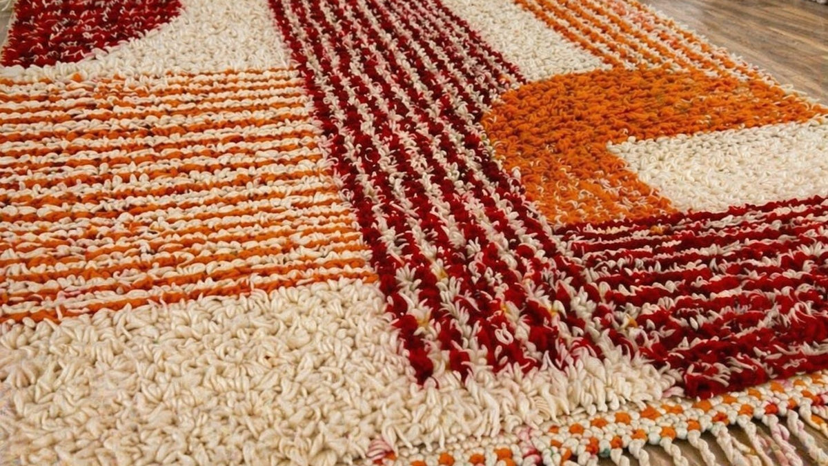 Gros plan sur la laine du tapis berbère Tawwurt, poil orange et bordeaux noué à la main