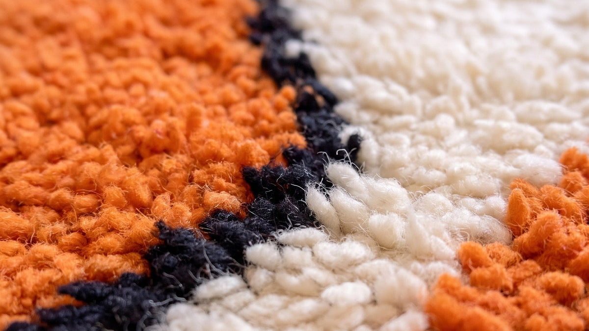 Gros plan sur la laine du tapis berbère Sourzan, poil orange noué à la main