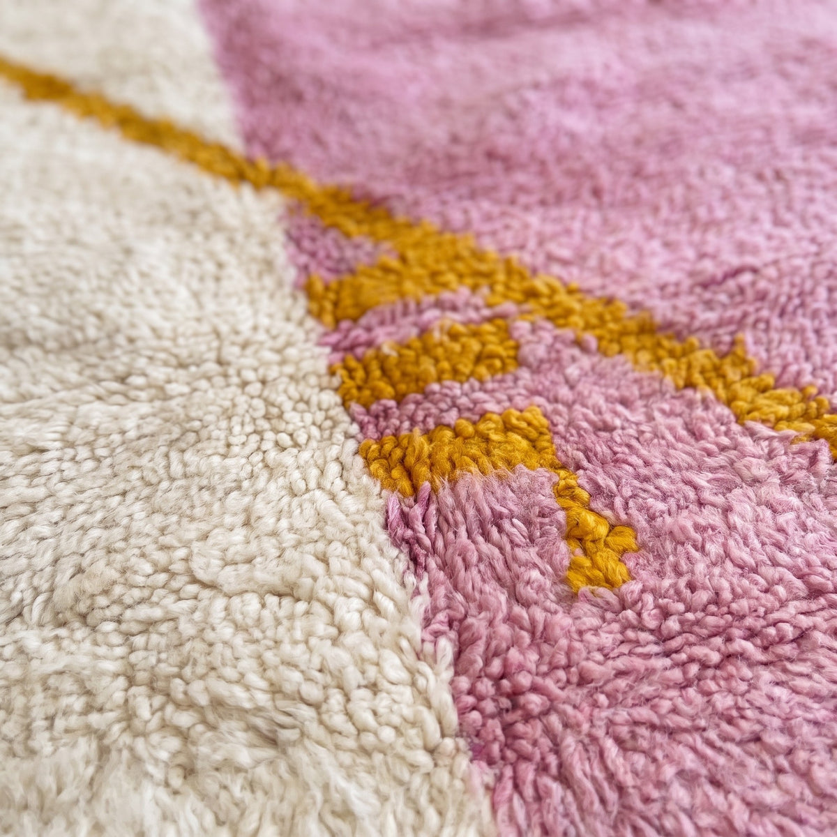 Gros plan sur un motif du tapis berbère Amanouz, champ partagé verticalement, moitié écrue à gauche