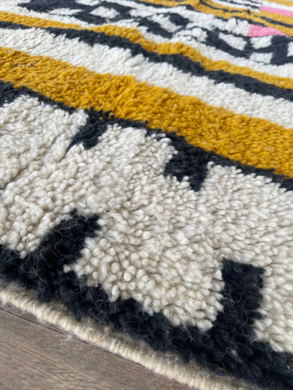 Gros plan sur le coin relevé du tapis berbère Timidarte, épaisseur du poil long et dos tissé à la main