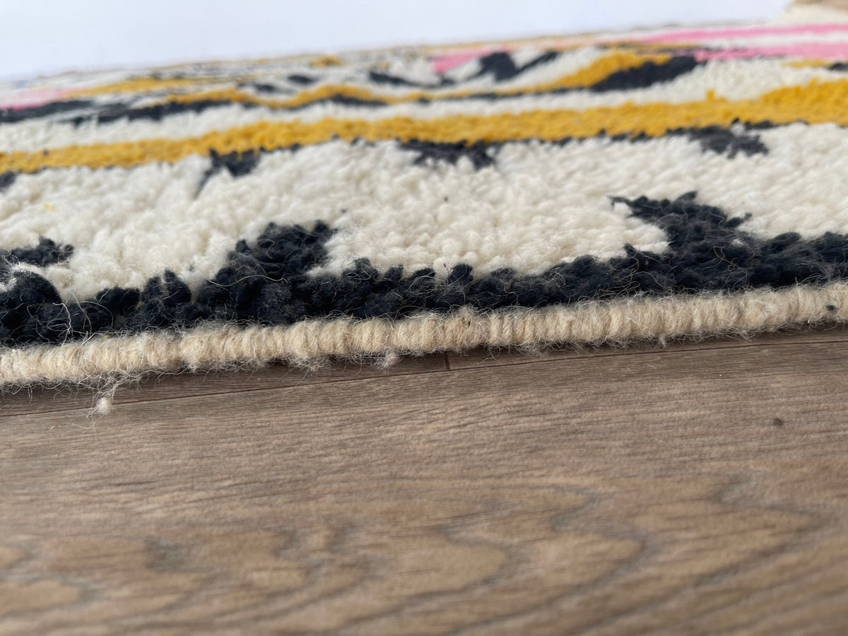 Gros plan sur le coin relevé du tapis berbère Timidarte, bordure et envers visibles de près