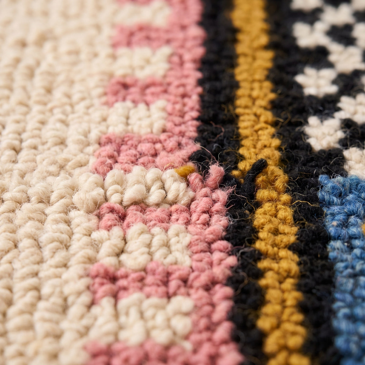 Gros plan sur un motif du tapis berbère Timidarte, fond écru à poil long, trois barres roses