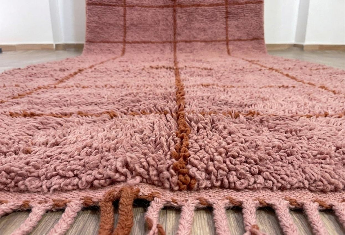 Close-up of the fringes on the Imassine Berber rug, pink and rust, at the bottom only, knotted by hand