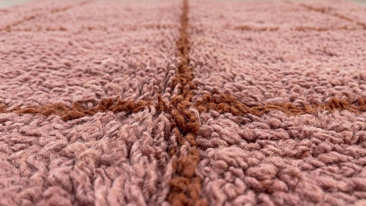 Gros plan sur la laine du tapis berbère Imassine, poil rose et rouille noué à la main