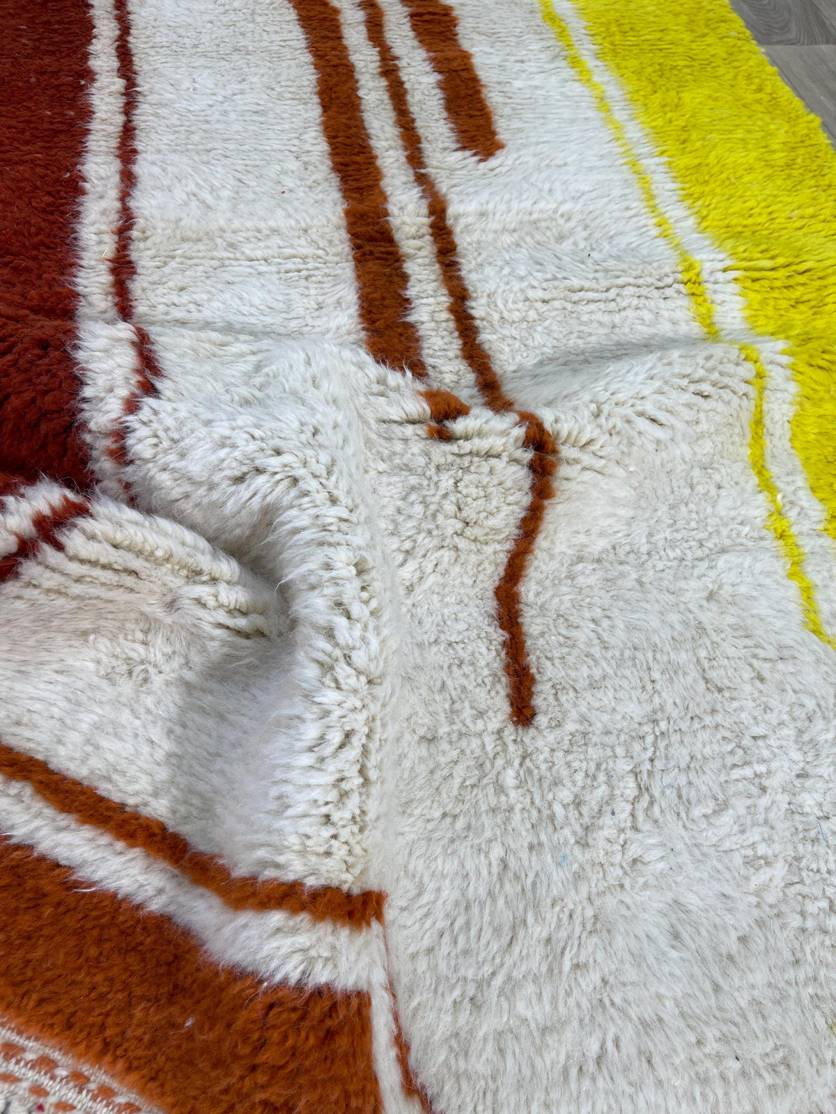Close-up of a detail of the Haouza Berber rug, long pile and rust and yellow pattern up close