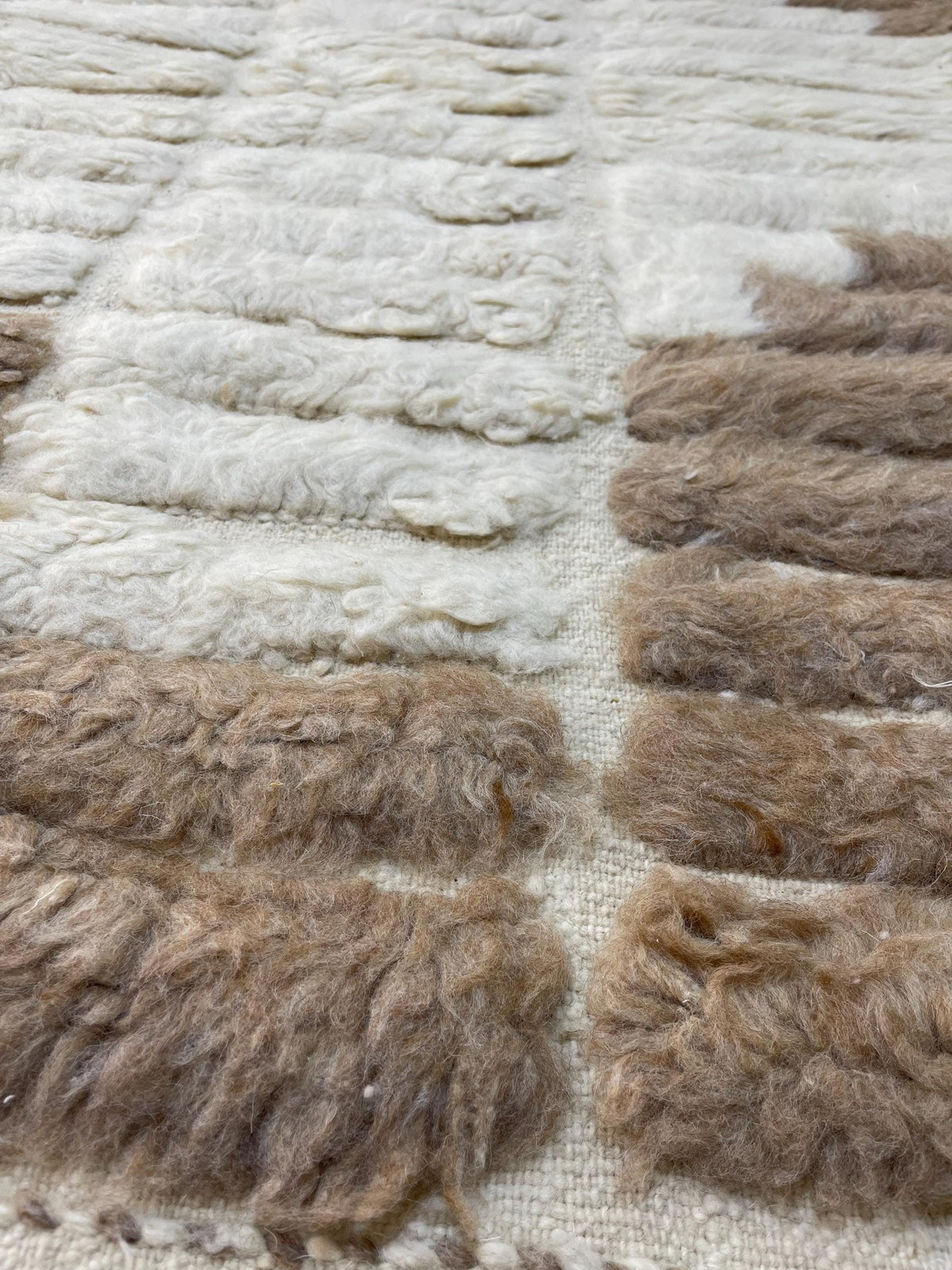 Gros plan sur la laine du tapis berbère Tarkeddit, relief de la laine et du motif à la lumière