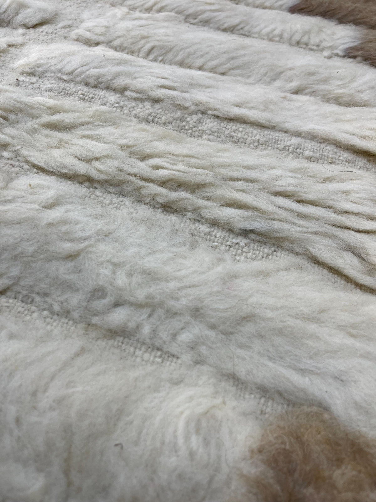 Gros plan sur la laine du tapis berbère Tarkeddit, laine de mouton au poil long, taupe et blanche, vue 5