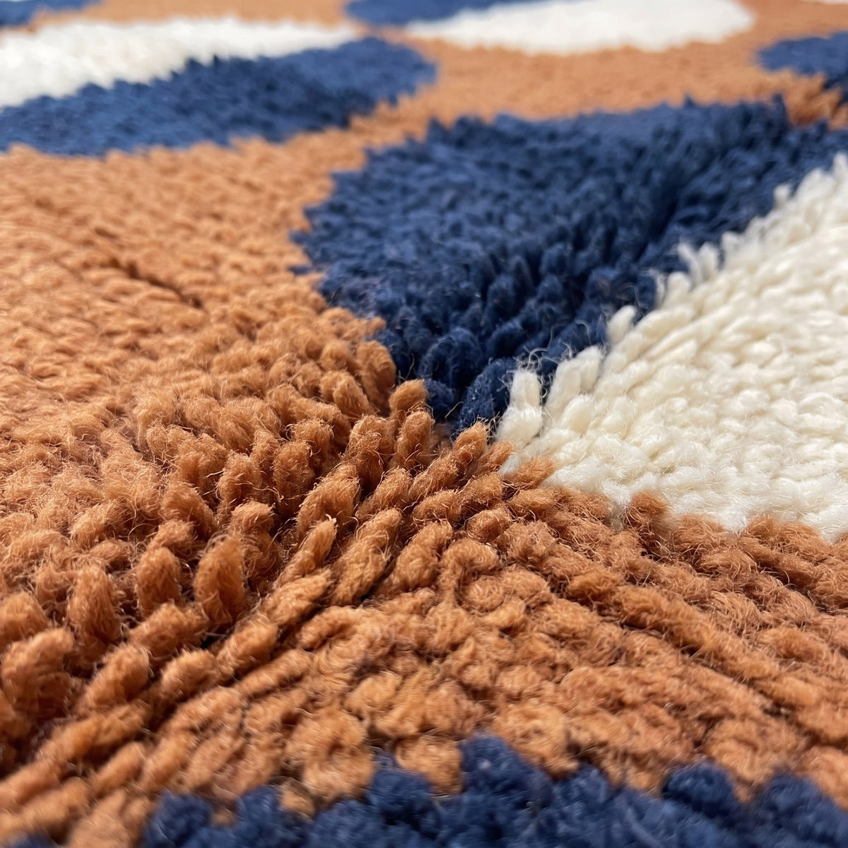 Gros plan sur un motif du tapis berbère Ziri, fond cognac, six rangées de demi-disques bleu marine
