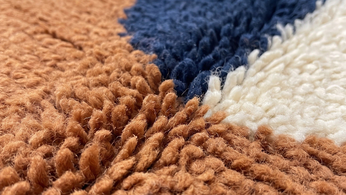 Gros plan sur la laine du tapis berbère Ziri, poil terracotta et bleu nuit