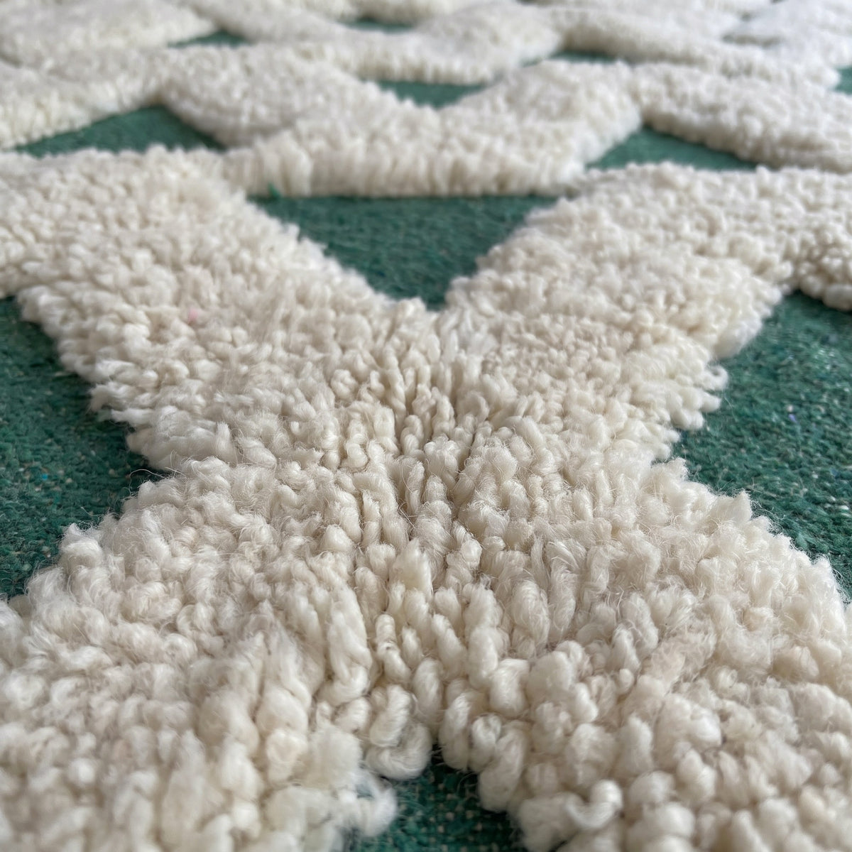 Gros plan sur un motif du tapis berbère Sezlan, zigzags emboîtés laissant sept rangées de triangles verts