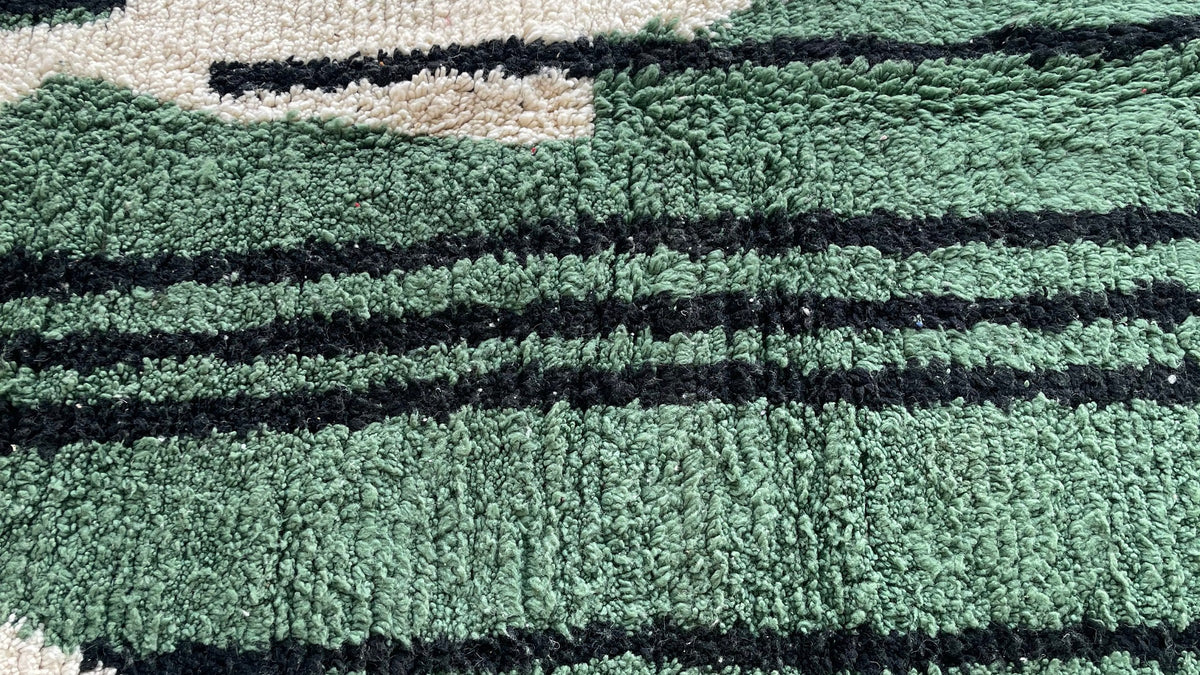 Gros plan sur la laine du tapis berbère Azrou, poil vert et noir noué à la main