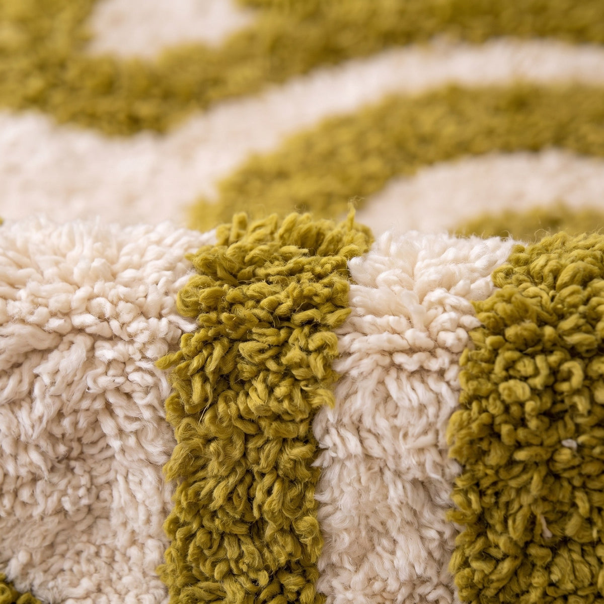 Gros plan sur un motif du tapis berbère Nerilt, fond crème à poil long, formes vert olive