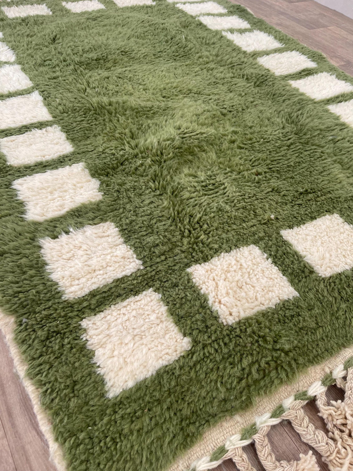 Gros plan sur le coin relevé du tapis berbère Tazouta, épaisseur du poil long et dos tissé à la main