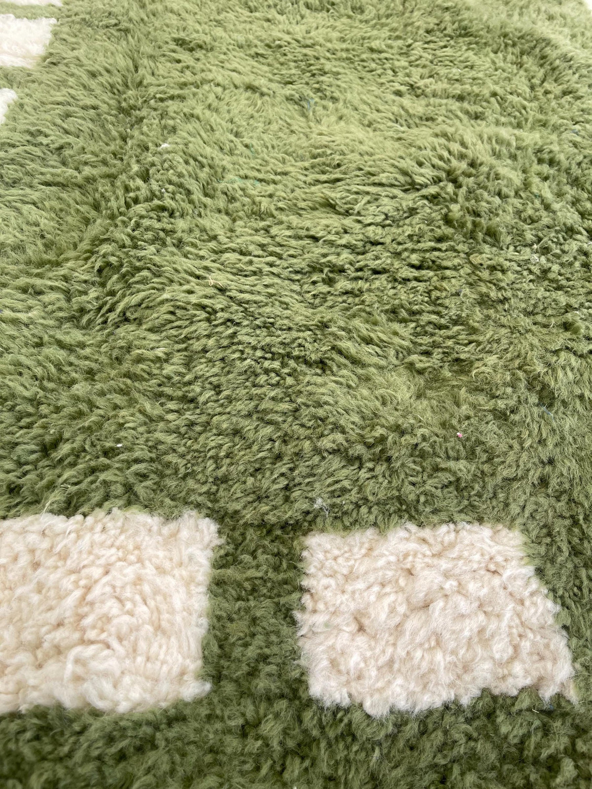 Gros plan sur la laine du tapis berbère Tazouta, laine de mouton au poil long, vert olive