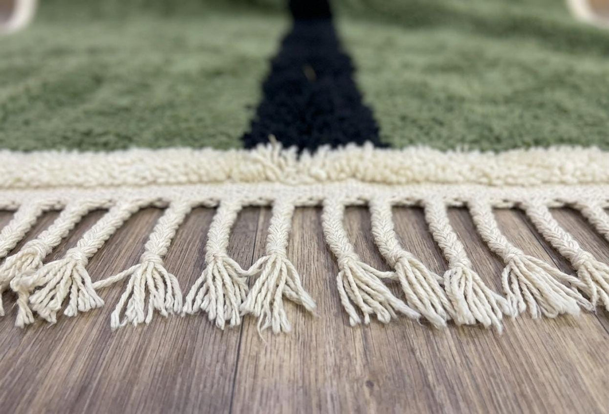 Gros plan sur les franges du tapis berbère Izoughar, écrues tressées en bas seulement, nouées à la main