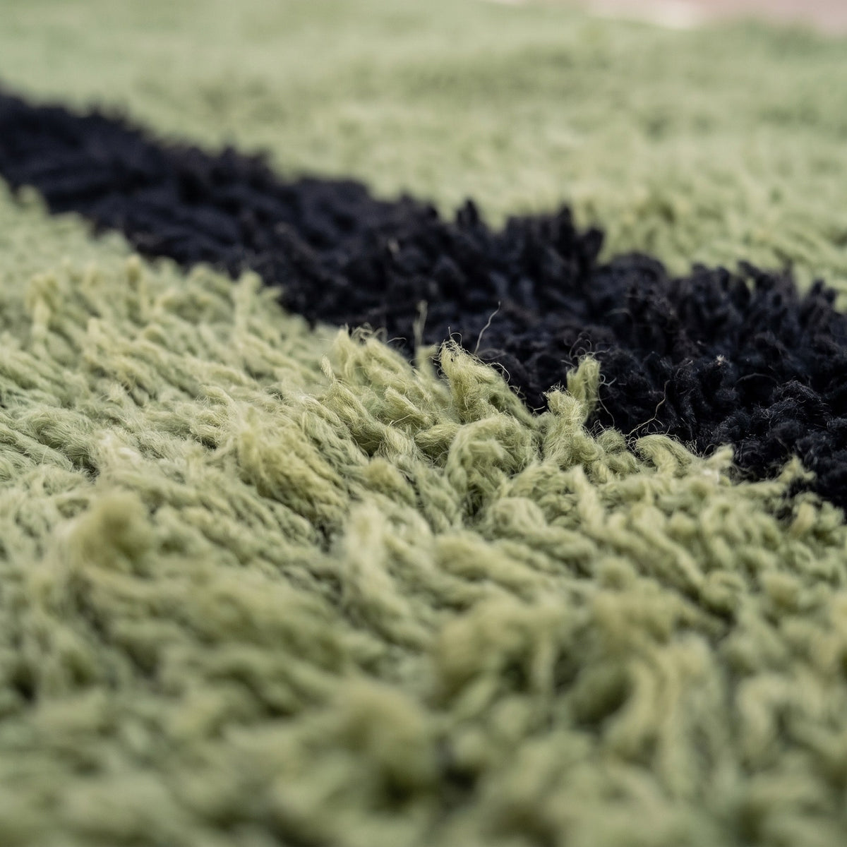 Gros plan sur un motif du tapis berbère Izoughar, champ vert sauge uni traversé