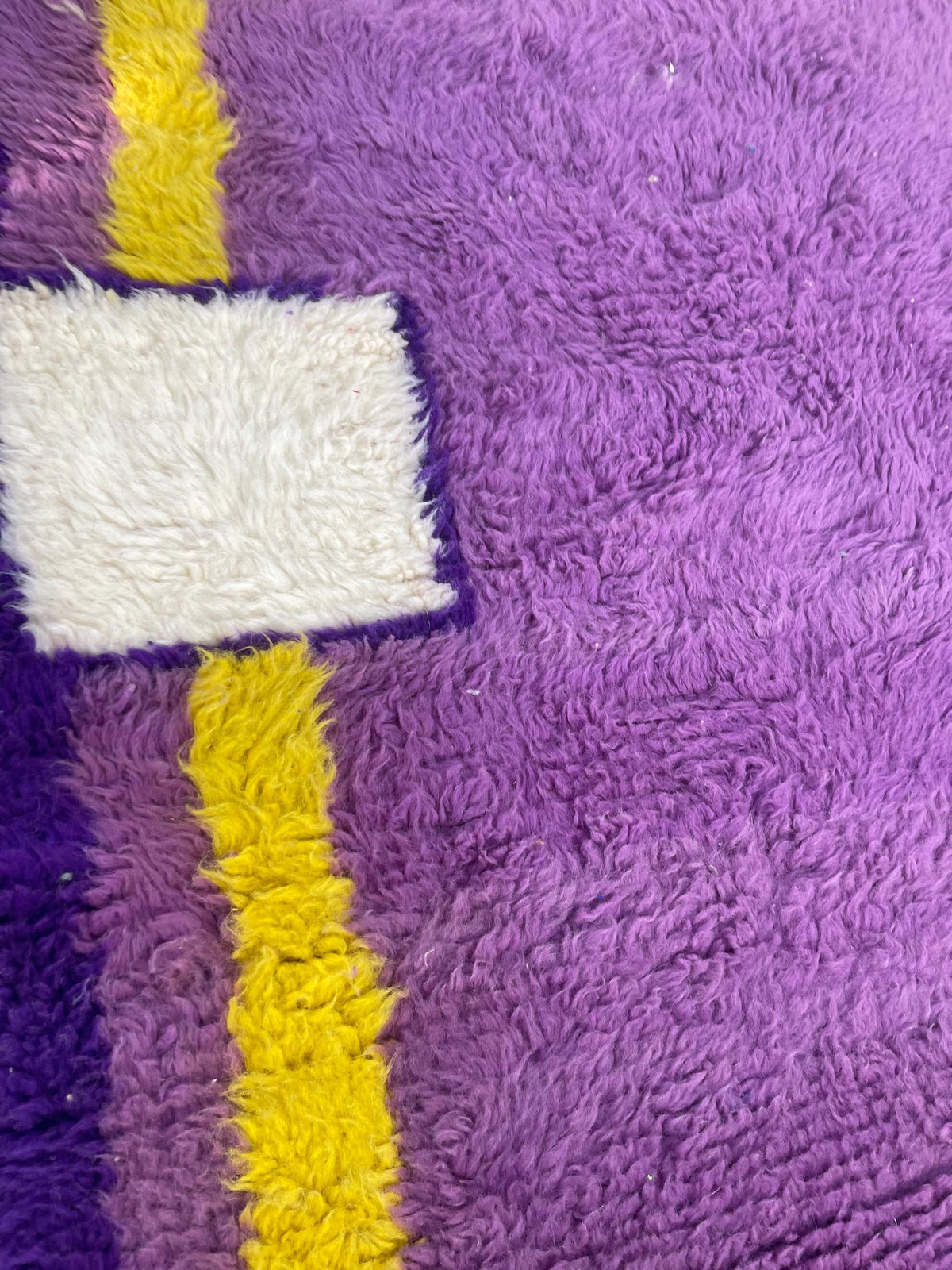 Gros plan sur la laine du tapis berbère Tamghra, texture de la laine naturelle et nuances du poil