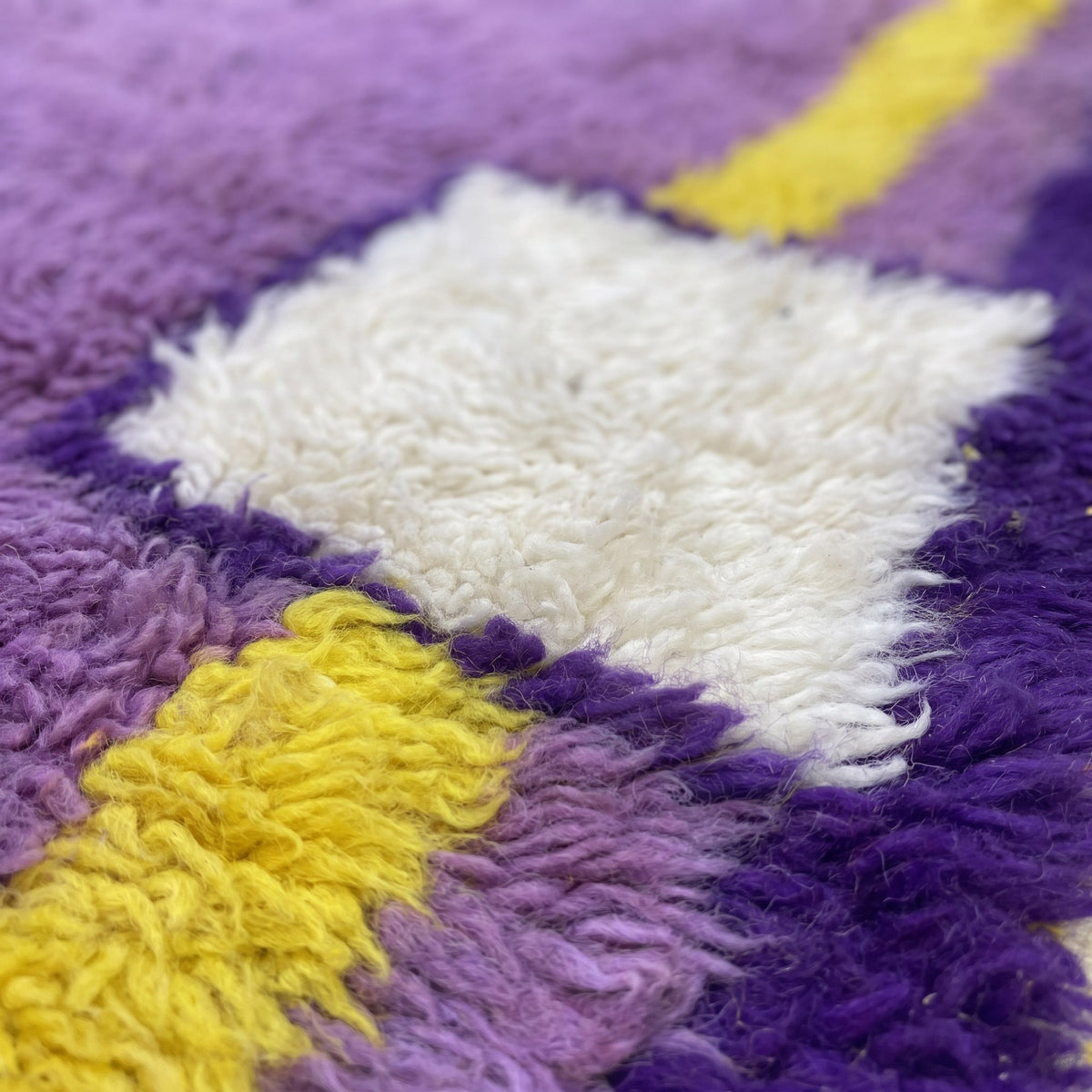 Gros plan sur un motif du tapis berbère Tamghra, champ violet uni encadré d'un filet jaune