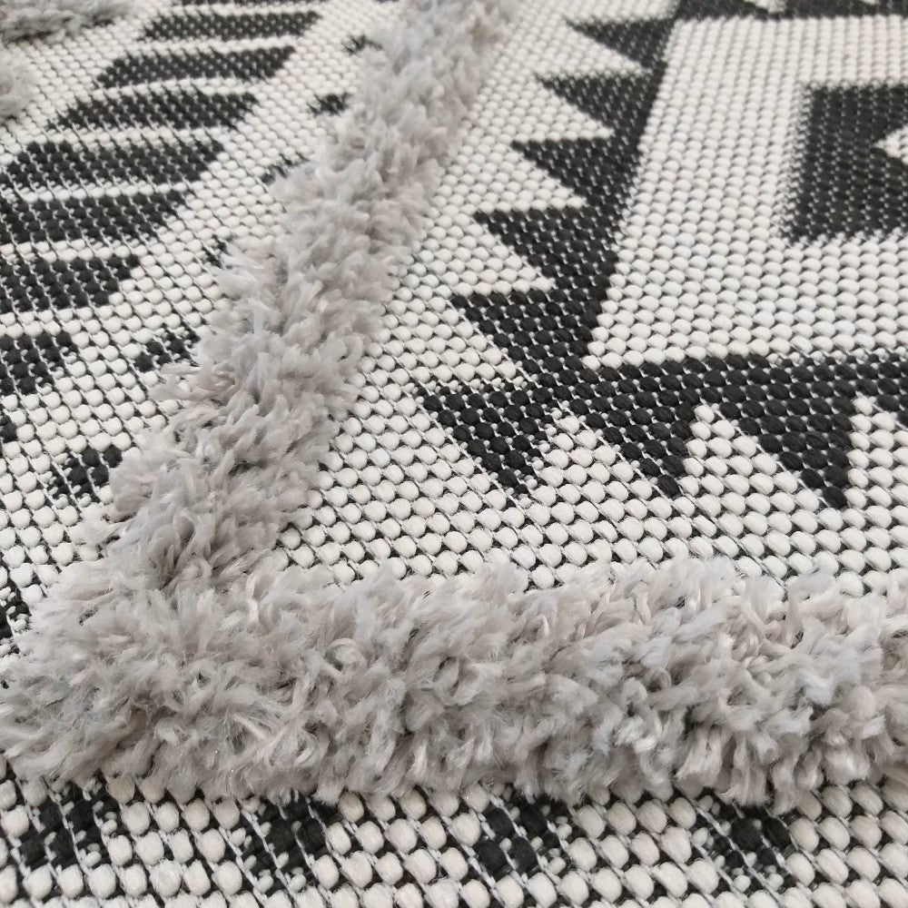 Tapis bicolore noir et blanc aux motifs géométriques tissés, accentué par des bandes gris clair en relief à l'aspect shaggy