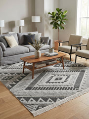 Tapis rectangulaire gris clair et foncé, à motifs géométriques berbères tissés et bouclés, dans un salon contemporain