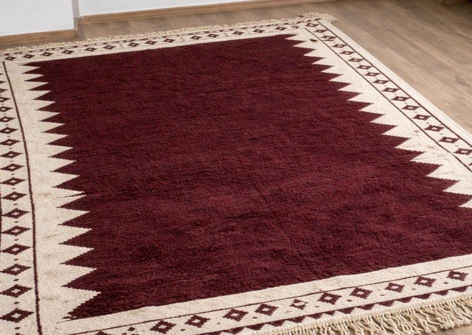 Gros plan sur un détail du tapis berbère Tasgalt, tissage plat et motif bordeaux et blanc vus de près