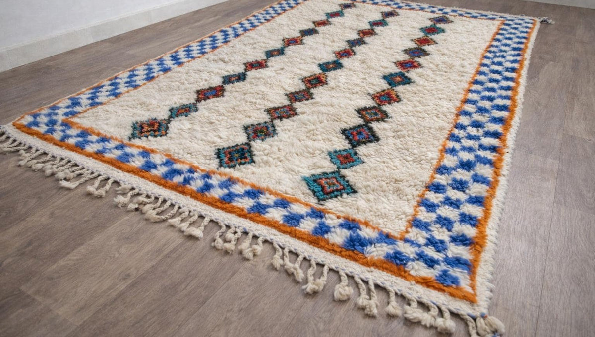 Tapis berbère style Azilal blanc et bleu Ifilan posé au sol vu de côté, noué main au Maroc