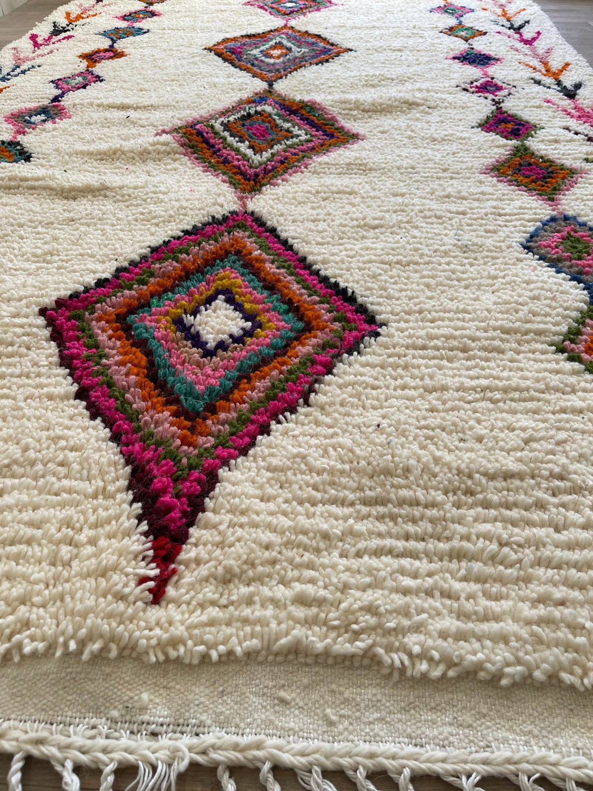 Gros plan sur la laine du tapis berbère Kessila, laine de mouton au poil long, blanche et fuchsia