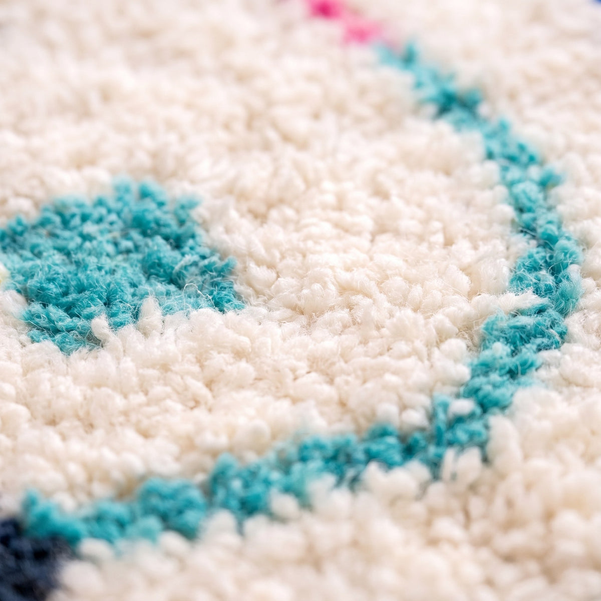 Gros plan sur un motif du tapis berbère Asekkil, fond ivoire, cadre ovale en traits bleus