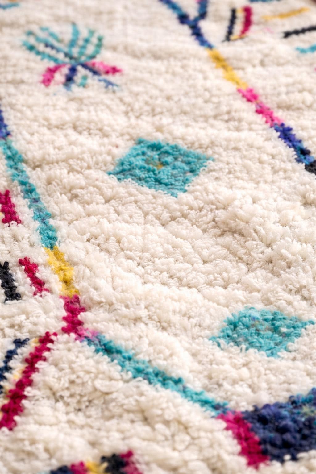 Gros plan sur la laine du tapis berbère Asekkil, poil blanc et multicolore noué à la main