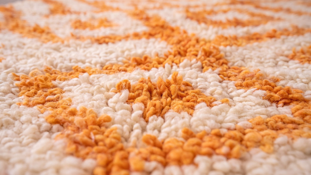 Gros plan sur la laine du tapis berbère Remlia, poil blanc et orange noué à la main