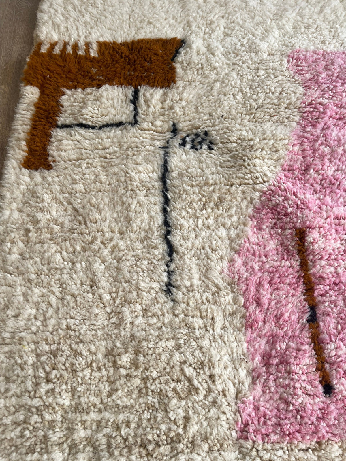 Gros plan sur la laine du tapis berbère Steha, laine de mouton au poil long, blanche et rose