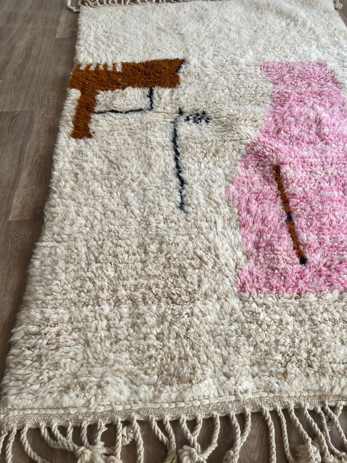 Gros plan sur un détail du tapis berbère Steha, poil long et motif blanc et rose vus de près
