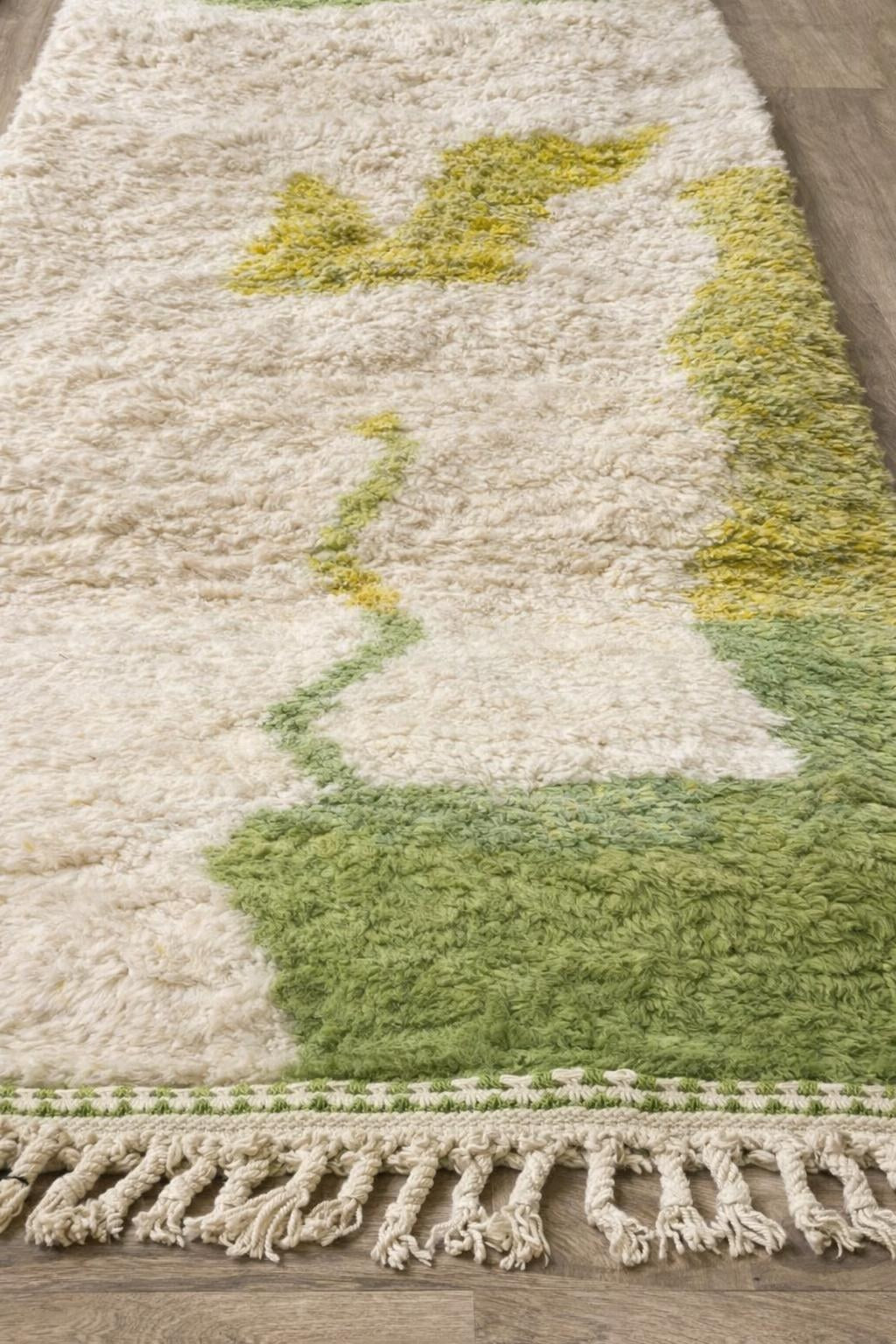 Gros plan sur un détail du tapis berbère Isulan, poil long et motif blanc et vert vus de près