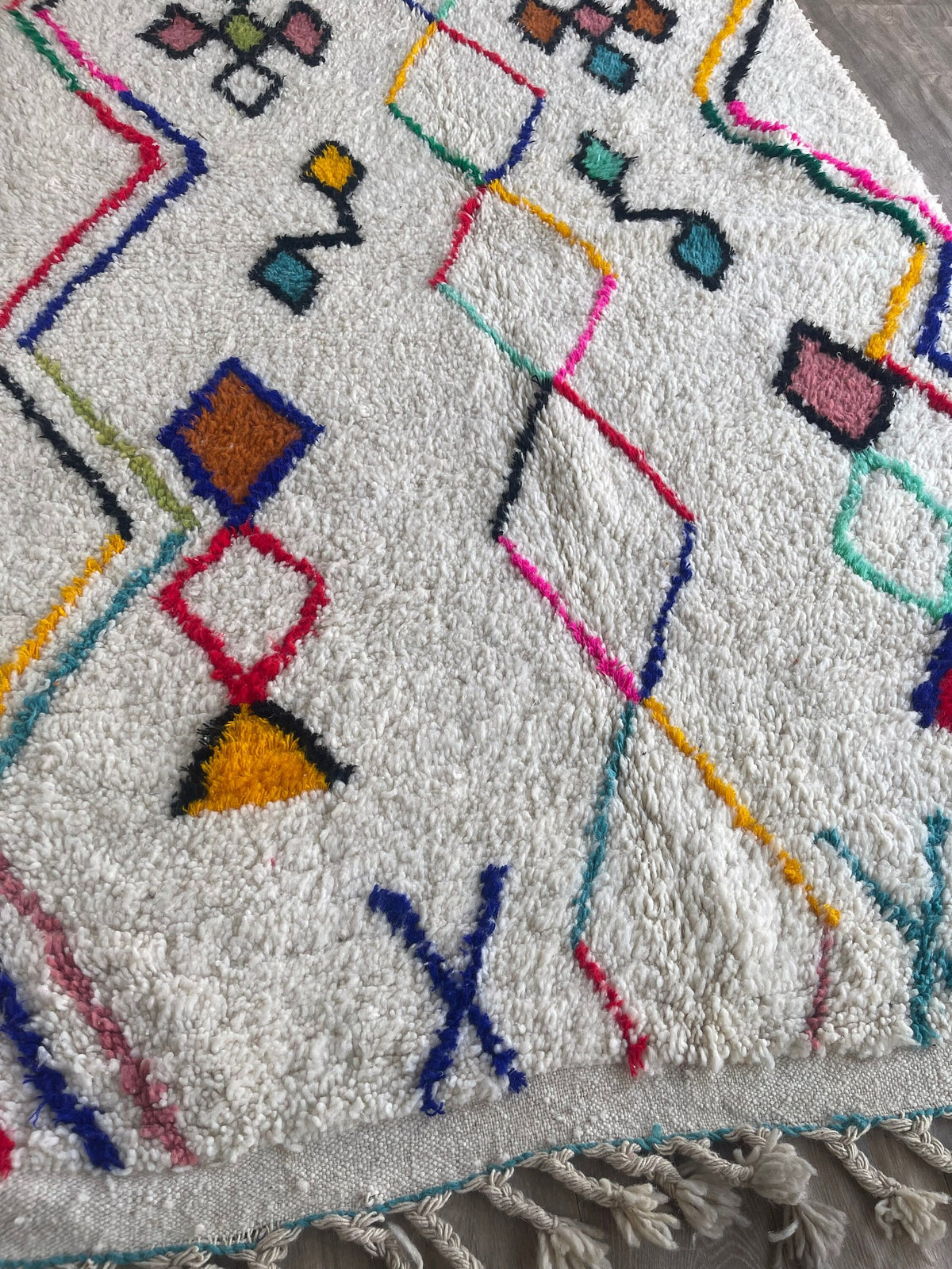 Gros plan sur le coin relevé du tapis berbère Tafirwa, bordure et envers visibles de près