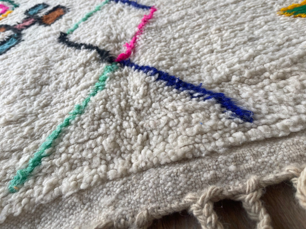 Gros plan sur le coin relevé du tapis berbère Tafirwa, angle du tapis et finition de la bordure