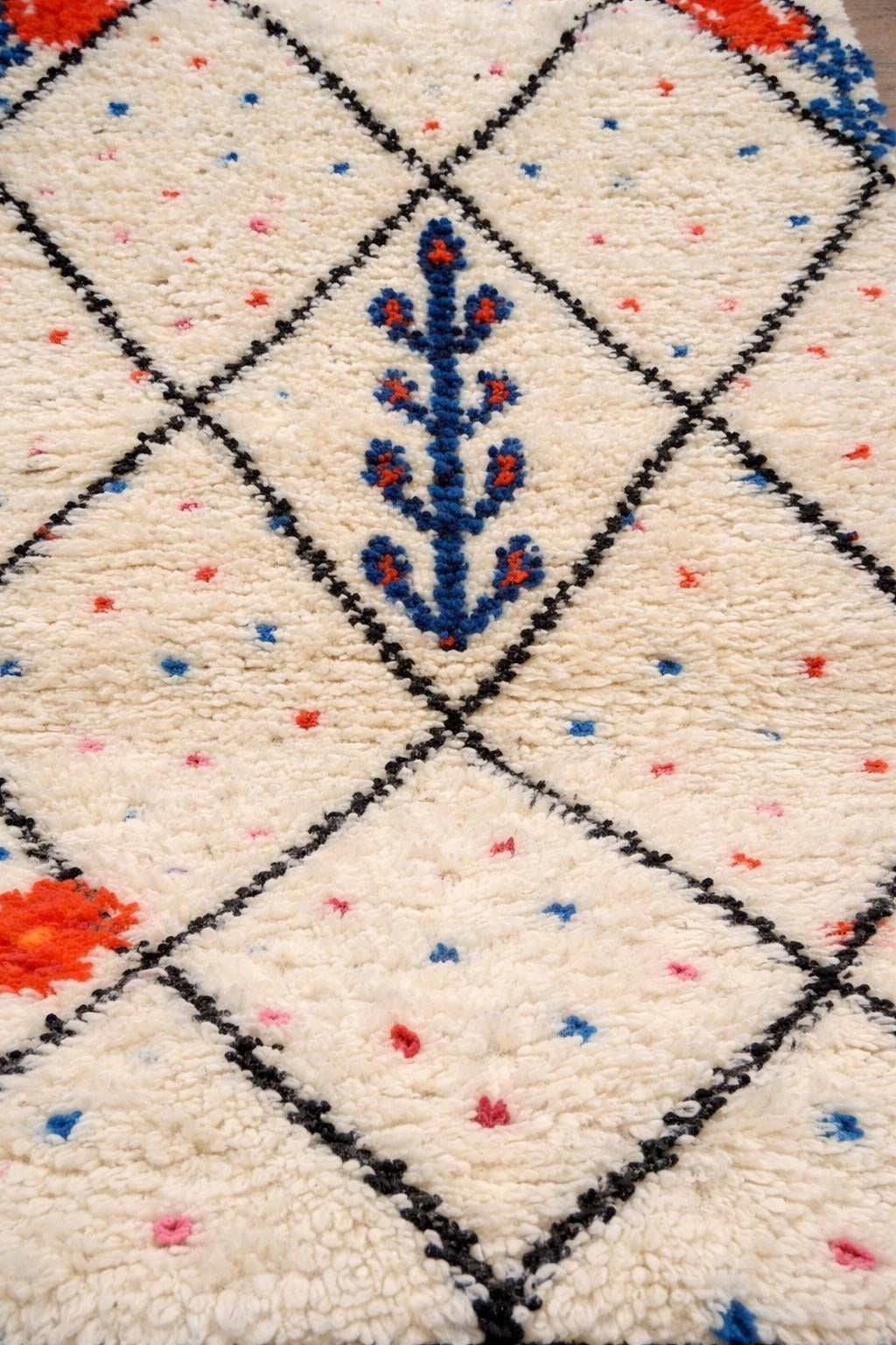 Gros plan sur la laine du tapis berbère Timichi, laine de mouton au poil long, blanche, noire et bleue