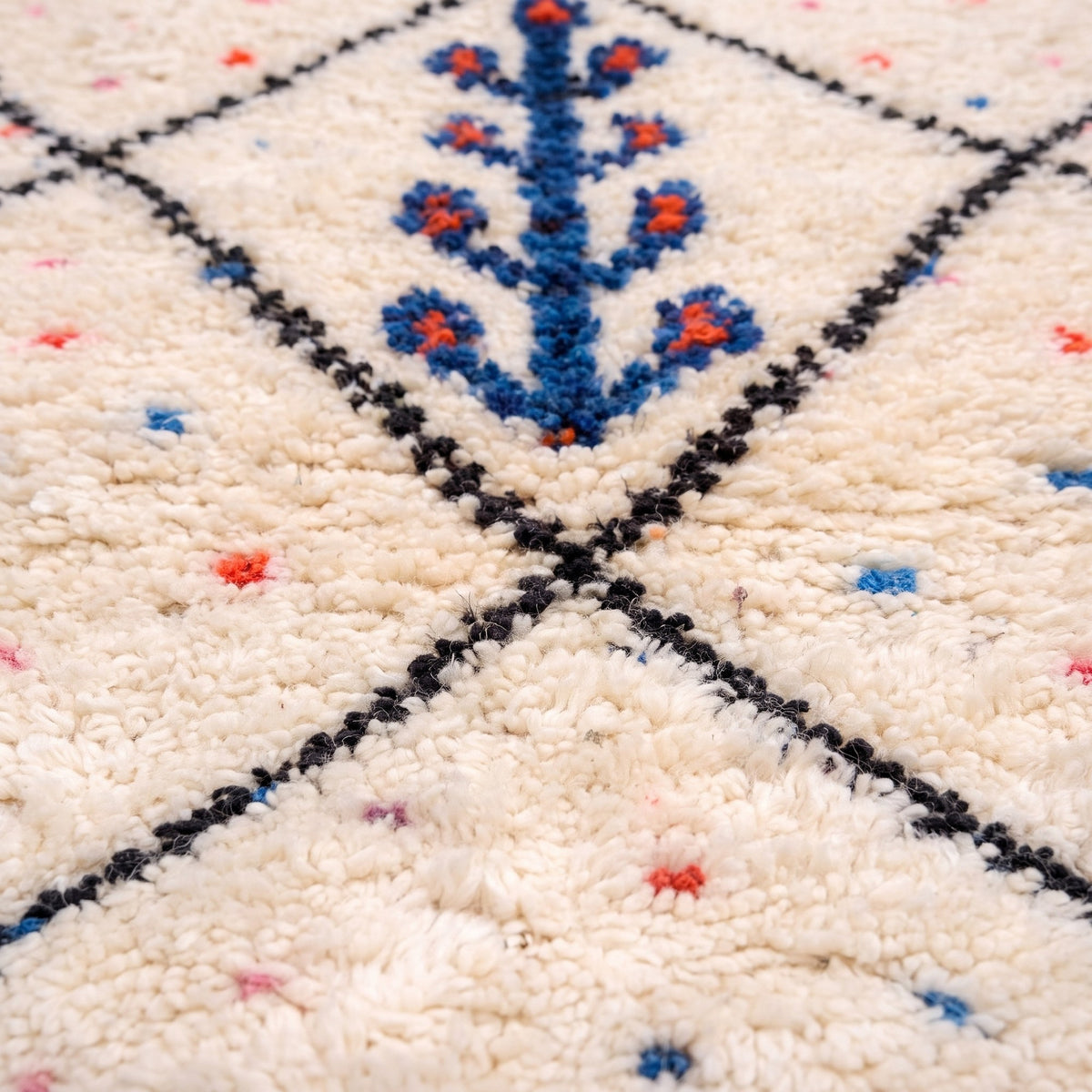 Gros plan sur un motif du tapis berbère Timichi, champ ivoire, treillis noir de losanges