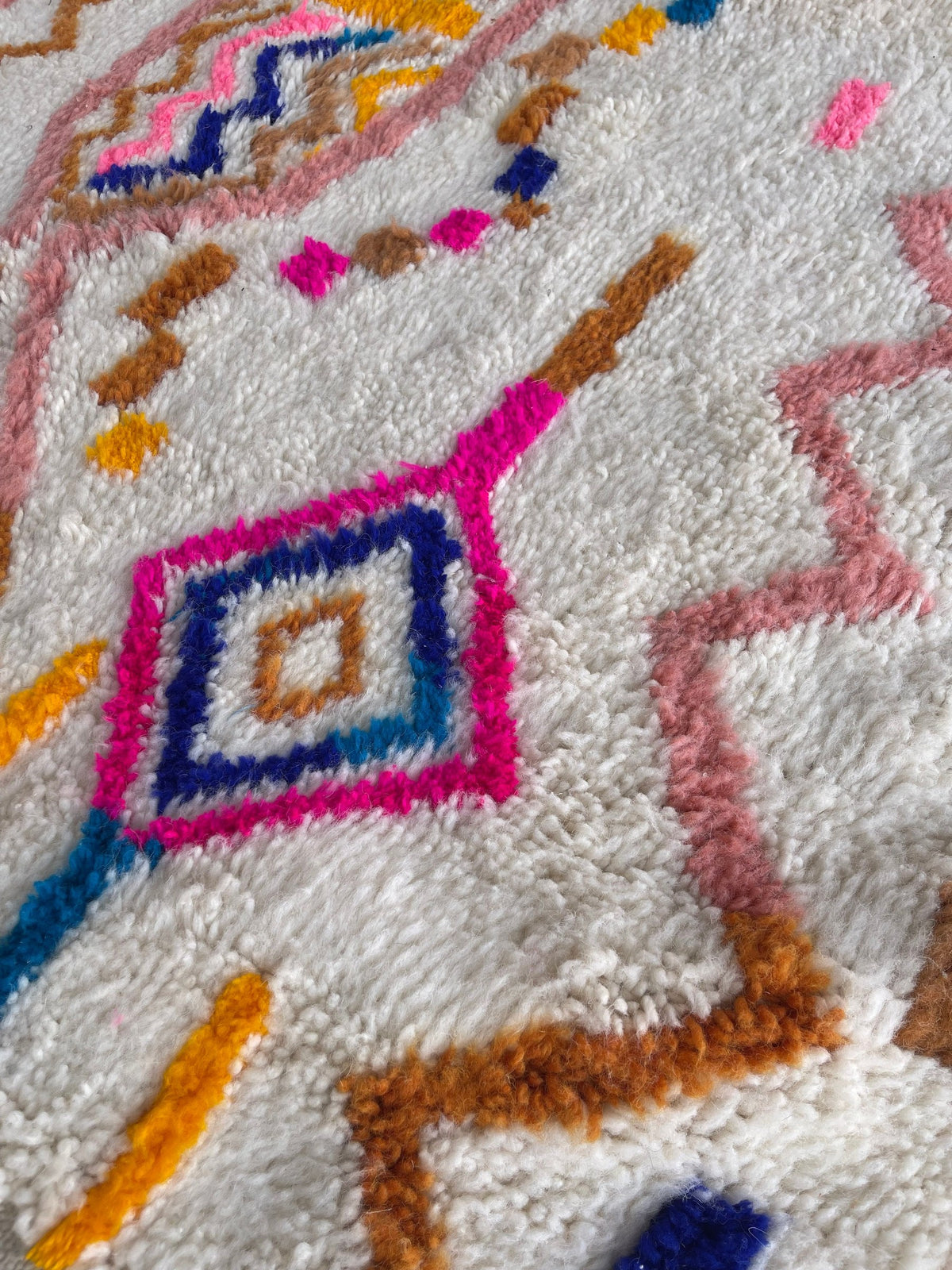 Gros plan sur la laine du tapis berbère Demnate, nœuds serrés et tracé du motif de près