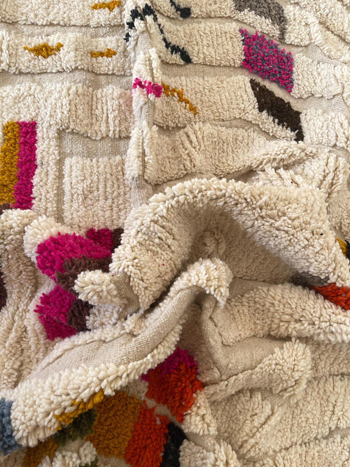 Gros plan sur un détail du tapis berbère Rezgad, poil long et motif multicolore vus de près
