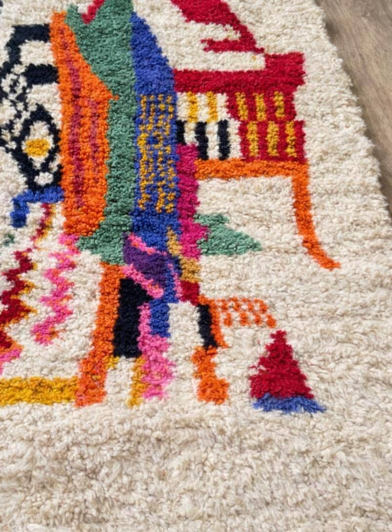 Gros plan sur un détail du tapis berbère Tamawayt, poil long et motif multicolore vus de près